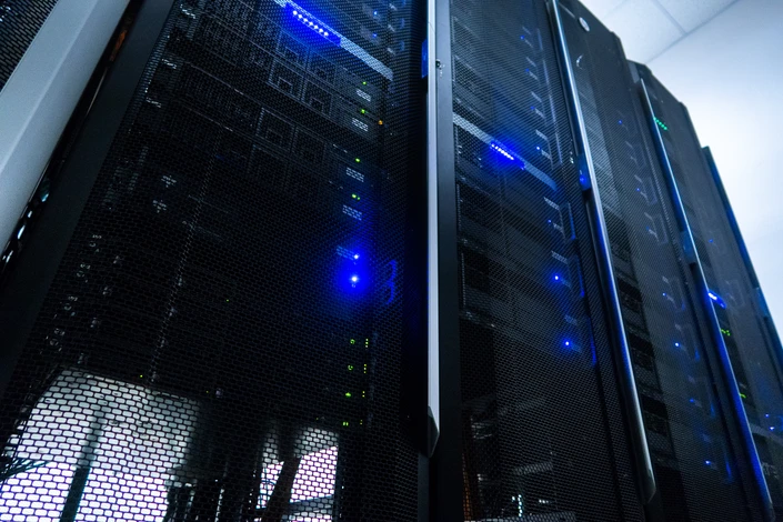 Salle de serveurs informatiques avec allées centrales, alignements de baies serveurs des deux côtés